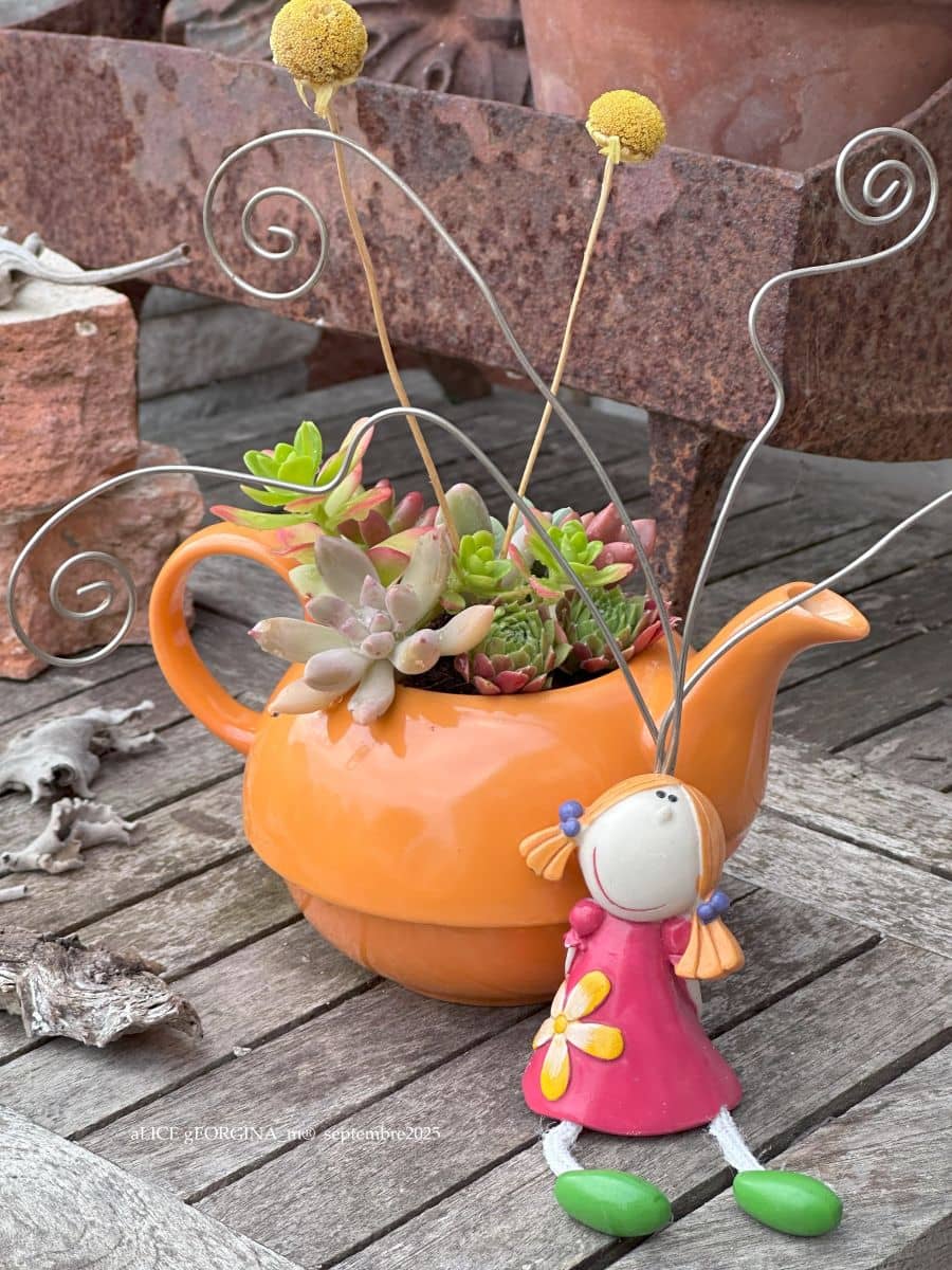PhotoCall Composition végétale de plantes succulentes avec une théière en céramique orange et un personnage porte photos en résine rose et vert
