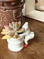 Composition végétale de plantes succulentes avec un pot miniature en porcelaine orné d'une souris miniature en jupe