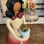 Composition végétale de plantes succulentes avec une statuette femme en terre tenant un pot