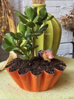 Composition végétale de plantes succulentes avec un moule à brioche en métal orange, patiné et un phacochère miniature en terre vernissé