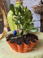 Composition végétale de plantes succulentes avec un moule à brioche en métal orange, patiné et un phacochère miniature en terre vernissé